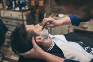 barber-shaving-customers-beard-in-vintage-barber-s-28LYREA