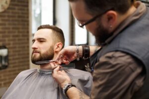 barber-styling-beard-with-scissors-to-client-at-ba-M5SCQBG