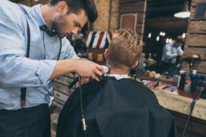 male-barber-cutting-hair-of-customer-in-barber-sho-W27A749