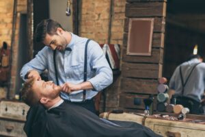 male-barber-trimming-customers-beard-in-barber-sho-2Z7Z6SP